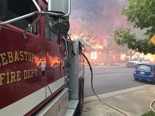 Sebastopol fire shot_preview Sebastopol fire engine parked off the street with hose trailing out from back, home in background engulfed in flames