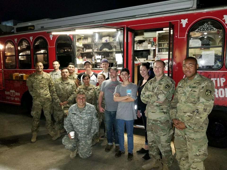 Tri tip trolley and troops_preview 9 military men and women dressed in camo standing in front of red catering trolley with 5 men and women who staff the trolley
